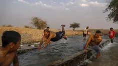 Warga Palestina meluncur di kanal air yang digunakan untuk irigasi untuk mendinginkan tubuh saat suhu udara mencapai 44 derajat Celcius di kota Jericho, Tepi Barat (1/9/2020). (AFP Photo/Ahmad Gharabli)