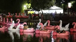 Orang-orang bersantai di atas balon flamingo saat mereka menonton film selama Festival Terapung pertama di Danau Sarah Kubstichek Brasilia, Brasil (30/9/2020). Warga bisa duduk santai di balon karet menonton film dan matahari terbenam di festival ini. (AP Photo/Eraldo Peres)