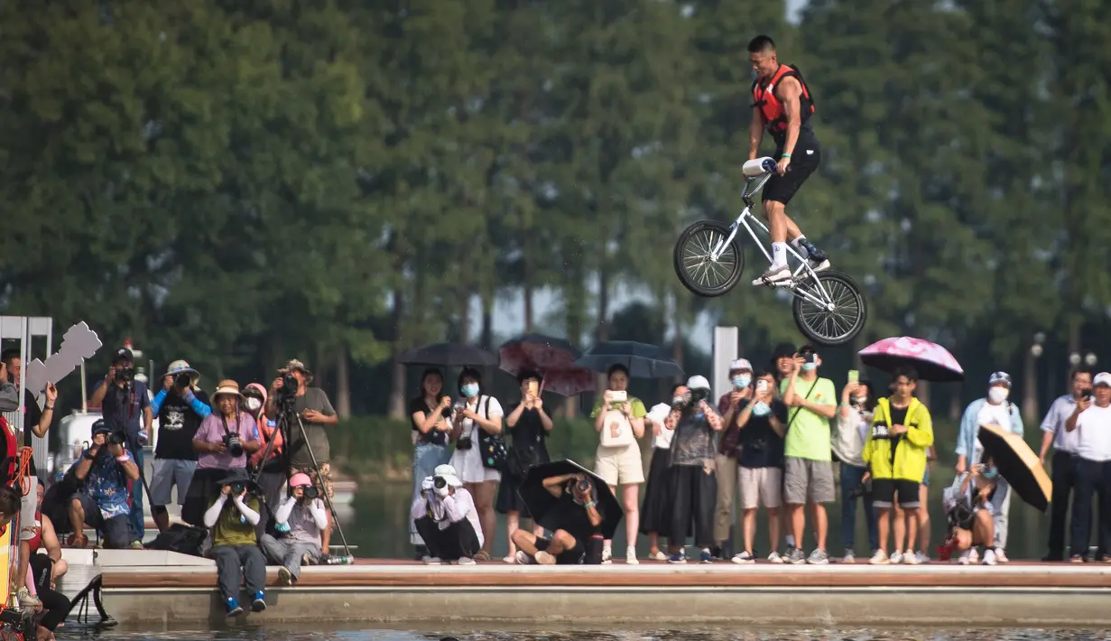Orang-orang menonton seorang pesepeda yang melompat ke Danau Timur menggunakan sepeda BMX dalam ajang tahunan festival lompat air (water jump) BMX di Wuhan, ibu kota Provinsi Hubei, China tengah, pada 22 Agustus 2020. (Xinhua/Xiao Yijiu)