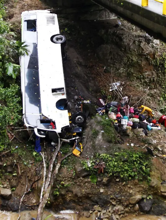 Petugas penyelamat melakukan evakuasi bus yang jatuh di jalan penghubung Medellin dan Bogota dekat San Luis, Provinsi Antiokia, Kolombia, 27 Desember 2021. Tujuh orang, termasuk seorang wanita hamil, tewas dan 20 lainnya luka-luka ketika sebuah bus terjun ke jurang. (Fredy BUILES/AFP)