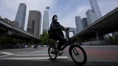 Seorang perempuan mengenakan masker berkendara melintasi persimpangan yang tenang di kawasan pusat bisnis saat perintah bekerja dari rumah di distrik Chaoyang, Beijing, Rabu (11/5/2022). Shanghai pada Rabu menegaskan kembali akan mempertahankan pendekatan &ldquo;nol-COVID&rdquo; pengendalian pandemi, sehari setelah kepala Organisasi Kesehatan Dunia (WHO) menyatakan kebijakan itu tidak berkelanjutan dan mendesak China mengubah strategi. (AP Photo/Andy Wong)