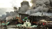 Para pekerja mencoba membantu memadamkan api di kapal nelayan di Pelabuhan Benoa, Denpasar, Bali, Senin (9/7). Kebakaran semakin membesar karena angin cukup kencang. (SONNY TUMBELAKA/AFP)