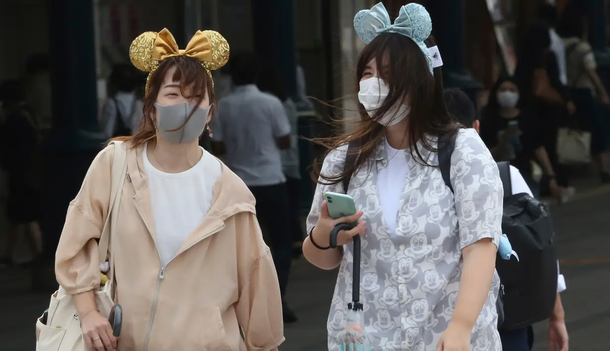 Pengunjung mengenakan masker guna melindungi diri dari virus corona berjalan menuju pintu masuk Tokyo Disneyland di Urayasu, dekat Tokyo, Rabu (1/7/2020). Tokyo Disneyland dibuka kembali untuk pertama kalinya dalam empat bulan setelah sempat ditutup karena penyebaran Covid-19. (AP/ Koji Sasahara)