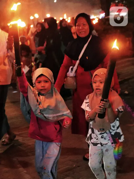 Anak-anak membawa obor sambil berkeliling kampung di kawasan Kota Tangerang, Banten, Jumat (29/7/2022) malam. Pawai obor tersebut digelar untuk menyambut malam pergantian Tahun Baru Islam atau 1 Muharam 1444 H. (Liputan6.com/Angga Yuniar)