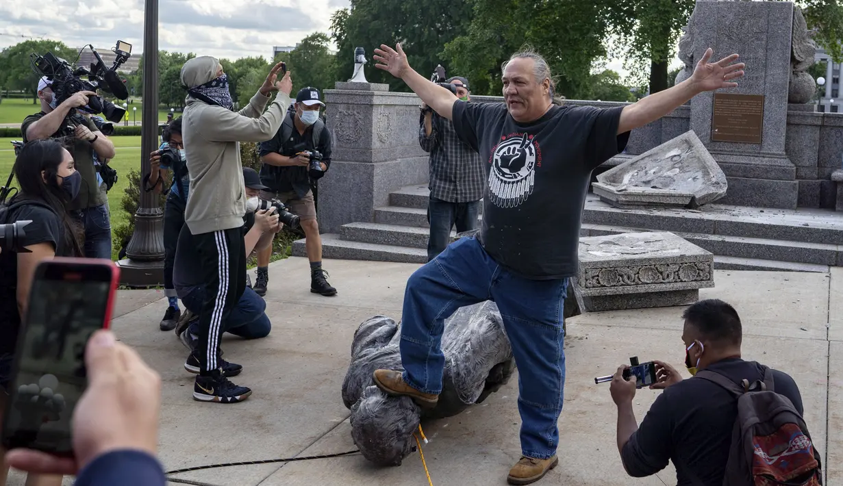 Anggota gerakan Indian Amerika Mike Forcia menginjak patung Christopher Columbus yang dirobohkan sekelompok massa di Minnesota State Capitol, St. Paul, Minnesota, Amerika Serikat, Rabu (10/6/2020). (Evan Frost/Minnesota Public Radio via AP)