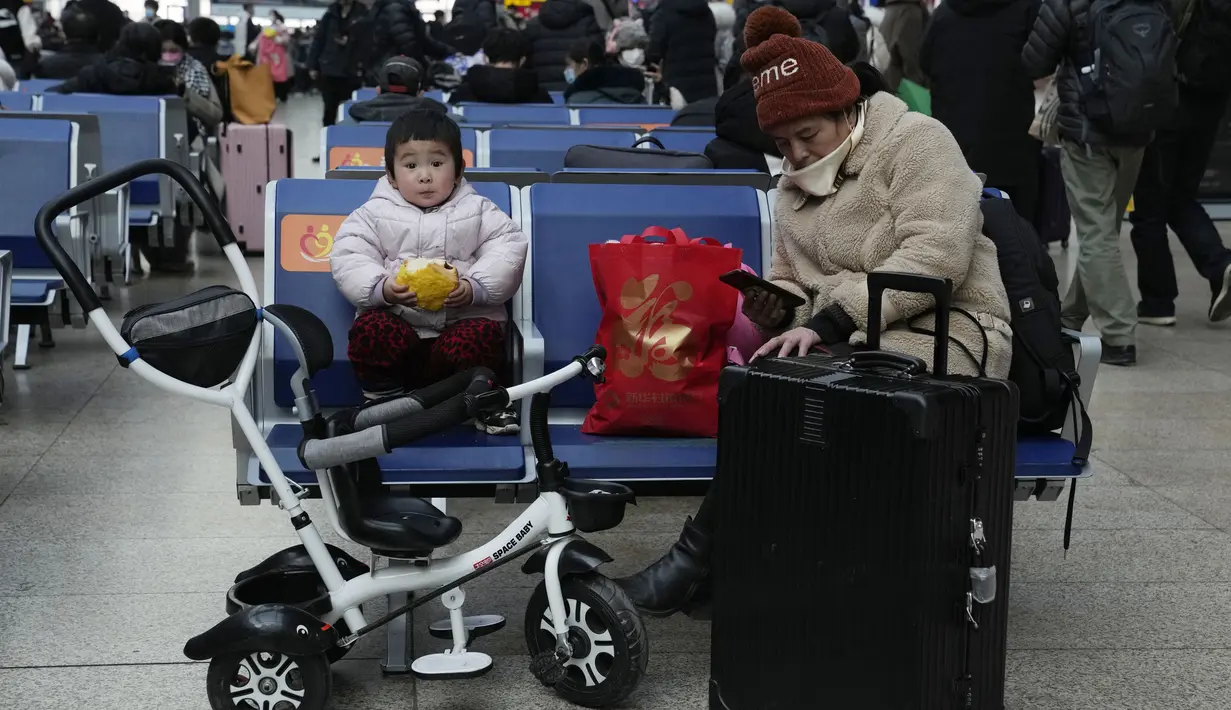Seorang anak makan roti sambil menunggu kereta api di Stasiun Kereta Selatan di Beijing, Chinan (14/1/2022). Partai Komunis yang berkuasa khawatir fakta ini bisa menghalangi ambisi mereka untuk meningkatkan kekayaan nasional dan pengaruh global. (AP Photo/Ng Han Guan)