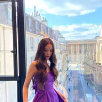 Jisoo Blackpink berpose mengenakan gaun ungu saat bersiap hadir di Dior Paris Fashion Show 2023. Gaun ungu strapless itu dari koleksi Dior. Gaun berpotongan A-line dan flowy juga memiliki hiasan pita di bagian belakang.  (Instagram/sooyaaa__)