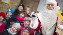Seorang pria berpakaian Santa Claus berpose dengan anak - anak di kantor pos desa Himmelpfort, Jerman, (10/11/2015).  Sudah anak - anak dari 80 negara mengirim surat kepada Santa Claus. (REUTERS/Hannibal Hanschke)