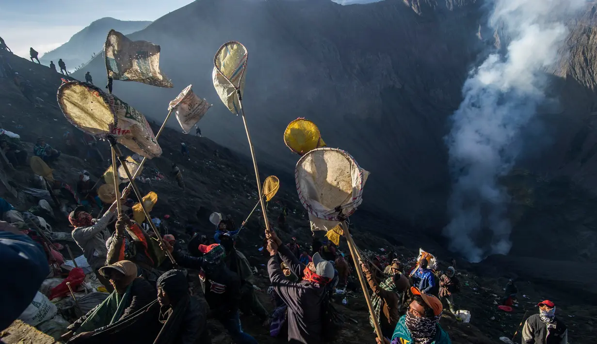 Warga berebut uang dan hasil bumi yang dilemparkan anggota suku Tengger selama Festival Yadnya Kasada di Probolinggo, Jawa Timur (10/7). Warga Tengger melakukan ritual lempar hasil bumi sebagai wujud syukur pada Sang Hyang Widi. (AFP Photo/Juni Kriswanto)