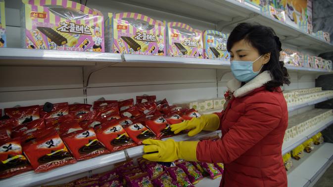Petugas memakai masker dan sarung tangan menata produk yang dijual di Pyongyang Department Store No. 1 saat penerapan standar protokol kesehatan di Pyongyang, Korea Utara (28/12/2020). (AFP/Kim Won Jin)
