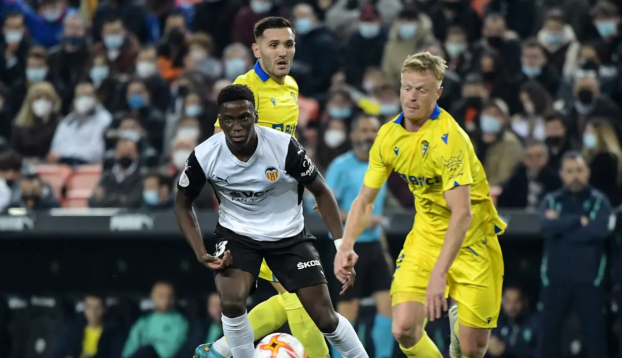 Gelandang Valencia, Ilaix Moriba (kiri) berusaha merebut bola dari gelandang Cadiz, Jens Jonsson selama pertandingan perempat final Piala Raja atau Copa del Rey di stadion Mestalla di Valencia 3/2/2022). Valencia menang tipis atas Cadiz 2-1 dan melaju ke semifinal. (AFP/Jose Jordan)