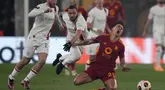 Pemain AS Roma, Paulo Dybala, terjatuh saat berusaha melewati pemain AC Milan, Ismael Bennacer, pada leg kedua perempat final Liga Europa di Stadion Olimpico, Roma, Jumat (19/4/2024). Giallorossi menang dengan skor 2-1. (AP Photo/Andrew Medichini)