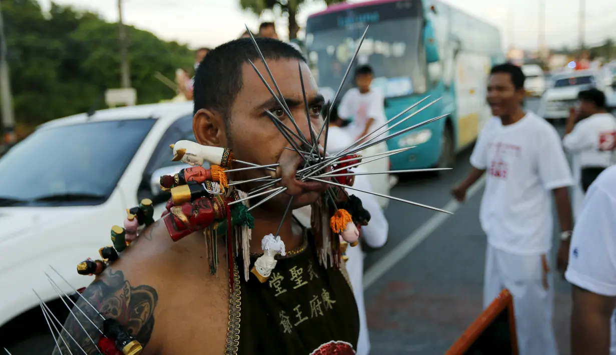 Seorang pemuja dari Kuil Samkong menusukkan senjata ke pipi saat memeriahkan festival vegetarian di Phuket, Thailand (17/10/2015). Festival ini menampilkan aksi ekstrem pemuja dengan menusukkan benda tajam ke wajah. (REUTERS/Jorge Silva)