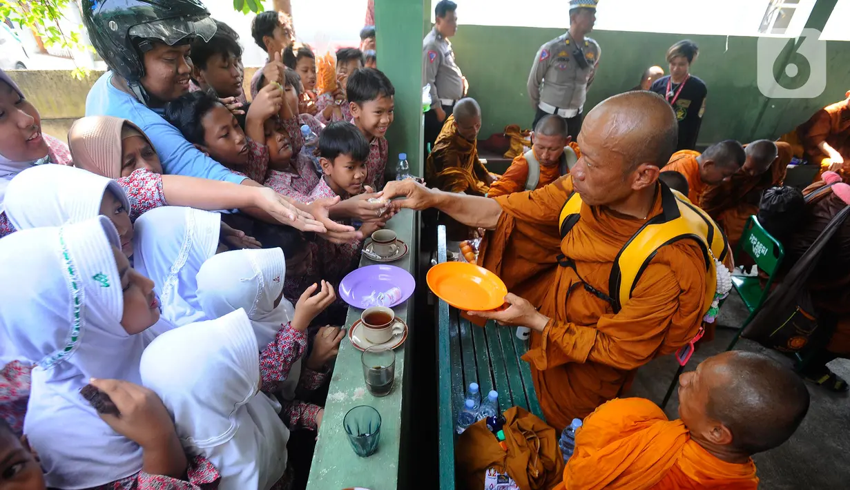 Seorang Biksu memberikan makanan kepada warga saat beristirahat setibanya di Pekalongan. (merdeka.com/Arie Basuki)