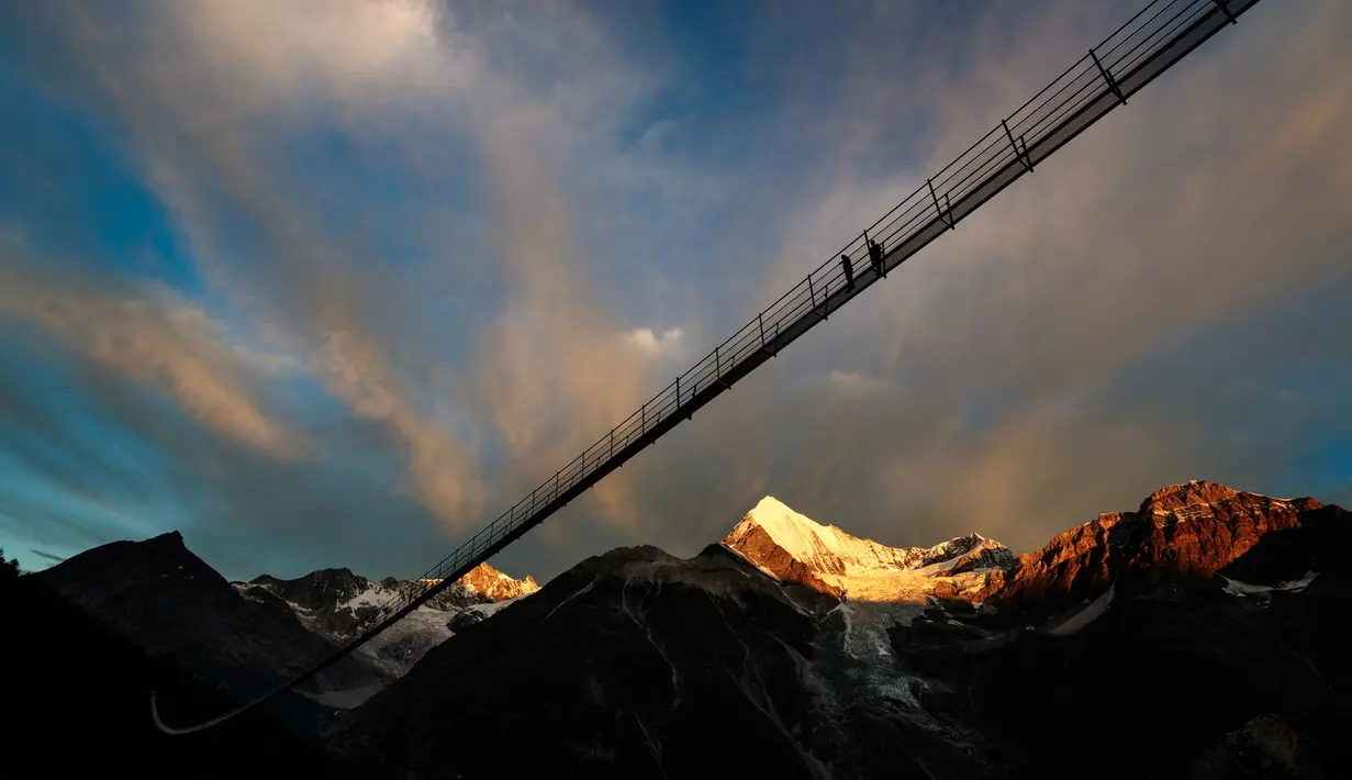 Pengunjung berjalan di jembatan gantung yang baru diresmikan di Zermatt, Swiss, 29 Juli 2017. Dewan Pariwisata Zermatt mengatakan jembatan ini merupakan yang terpanjang mengungguli jembatan serupa di Reutte, Austria. (Valentin Flauraud/Keystone via AP)