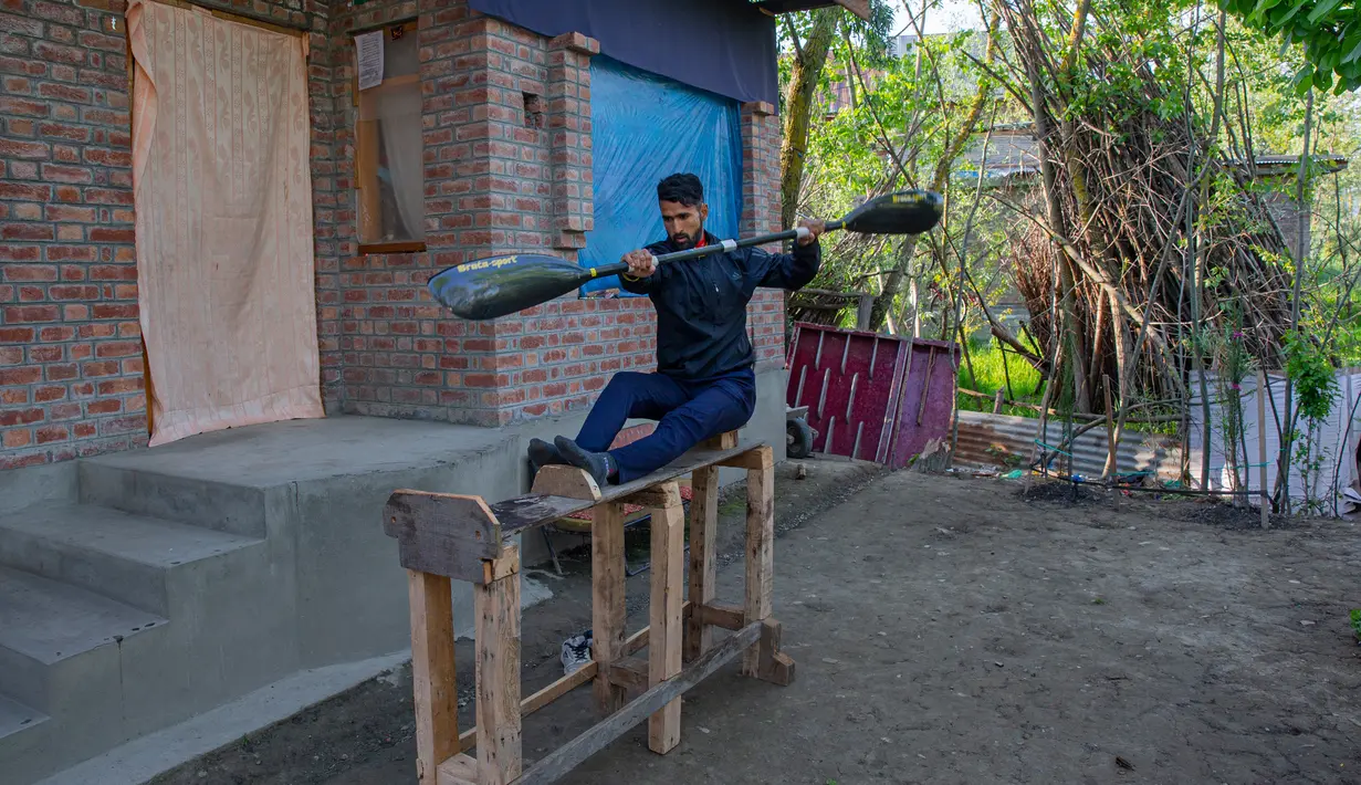 Atlet kayak Kashmir, Vilayat Hussain melakukan latihan pada ergometer kayu yang sedang dibangun di rumahnya di Srinagar pada 24 April 2020. Seperti atlet yang lain, Hussain harus menjalani latihan di rumah, namun lockdown bagi 7 juta penduduk Kashmir bukan hal yang baru. (AP Photo/Dar Yasin)