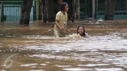 Dua anak bermain banjir di kawasan Tebet, Jakarta, Selasa (8/3/2016). Kawasan Tebet terendam banjir akibat meluapnya Sungai Ciliwung. (Liputan6.com/Gempur M Surya) 