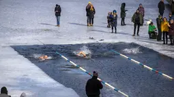 Para perenang bertanding saat kompetisi renang musim dingin di lubang es sepanjang 25 meter di sebuah danau dekat Vilnius, Lithuania, Sabtu (6/3/2021).  Suhu air saat itu 3 derajat Celcius, sedangkan udaranya -3 derajat Celsius. (AP Photo/Mindaugas Kulbis)