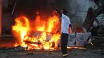 Seorang pria berdiri di dekat sebuah mobil yang terbakar setelah sebuah serangan bom di sebuah restoran di Mogadishu, Somalia (8/5). Setidaknya 6 orang tewas dan 10 orang lainnya terluka dalam serangan bom mobil tersebut. (AP Photo/Farah Abdi Warsameh)
