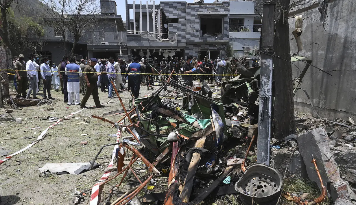 Petugas polisi, penyelidik, dan petugas penyelamat berkumpul di lokasi ledakan, di Lahore, Pakistan, Rabu (23/6/2021).  Beberapa bangunan di lokasi kejadian juga rusak akibat ledakan tersebut.  (AFP/Arif Ali)