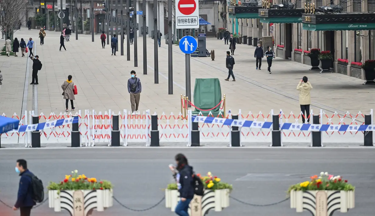 Orang-orang berjalan di sekitar Bund, sepanjang Sungai Huangpu, Puxi, Shanghai, 31 Maret 2022. Daerah Puxi akan lockdown mulai 1 April 2022. (Hector RETAMAL/AFP)