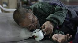 Victor Regis Ramirez, yang diusir dari rumah kontrakannya, minum dari cangkir saat berbaring di tempat tidur di tempat penampungan tunawisma di Asuncion, Paraguay, Jumat (2/7/2021). Menurut direktur National Emergency Office jumlah tunawisma telah meningkat di tengah pandemi. (Ap Photo/Jorge Saenz)