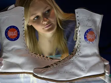 Pegawai menata sepatu boot yang dipakai dan ditandatangani oleh Muhammad Ali saat kejuaraan tinju melawan Jimmy Young pada 1975, dalam sesi pemotretan pameran tentang Ali bertajuk "I Am The Greatest", di O2 Arena, London, Kamis (3/3). (JUSTIN TALLIS/AFP)