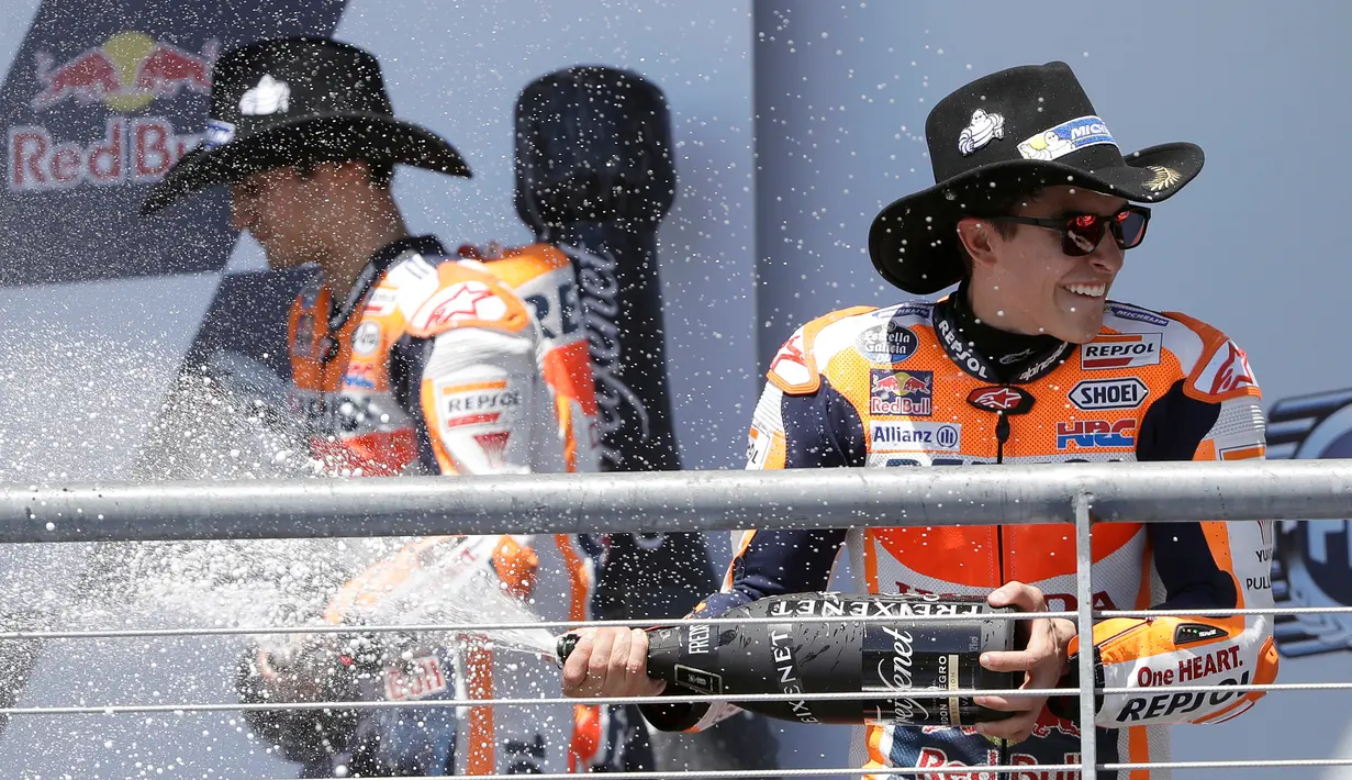 Marc Marquez menyemprotkan sampanye saat merayakan kemenangannya pada MotoGP Amerika di Austin, Texas, (23/4). Valentino Rossi meraih Posisi kedua dan posisi ketiga ditempati Dani Pederosa. (AP Photo/Eric Gay)