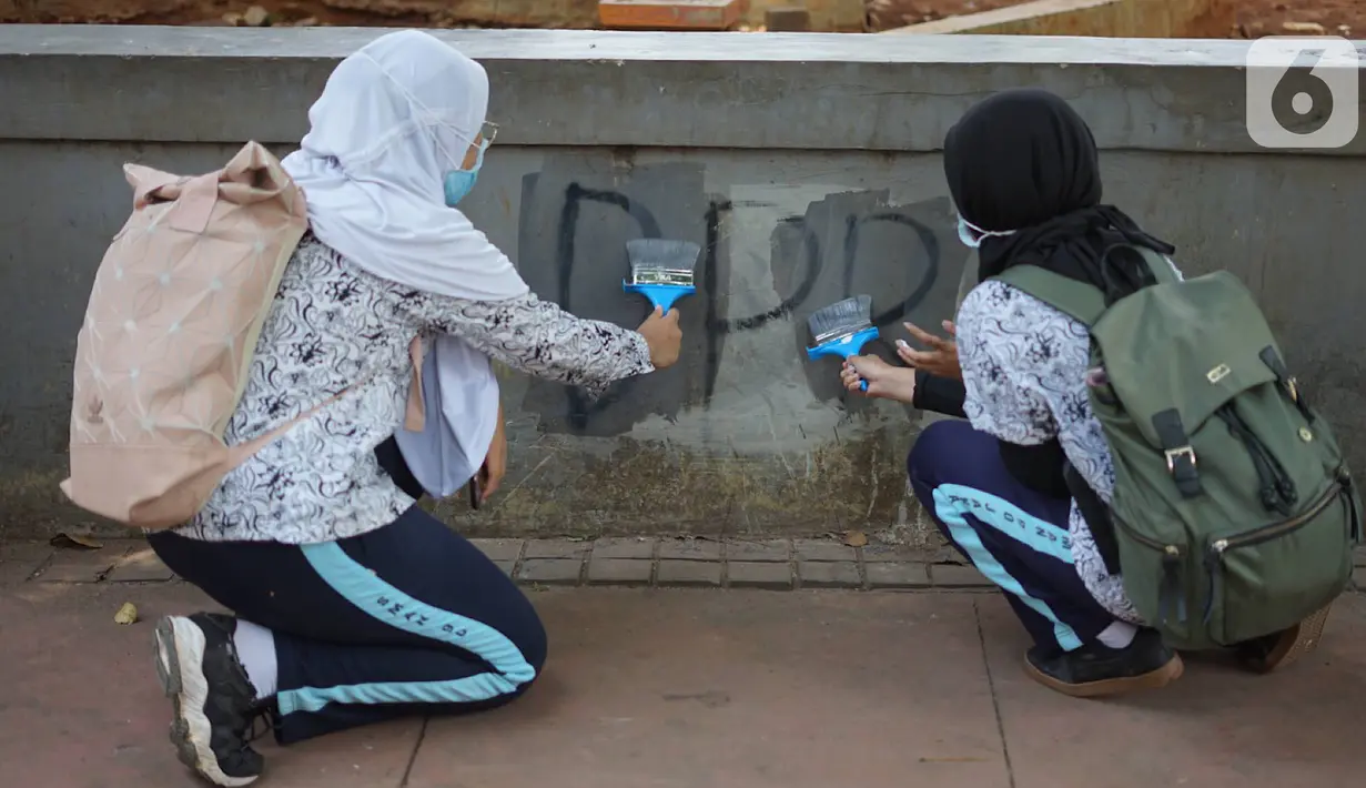 Pelajar mengecat  coretan yang mengotori tembok  saat kericuhan dalam unjuk rasa di Senayan, Jakarta, Jumat (4/10/2019). Para siswa dan alumni SMA menutup coret-coretan  itu sekaligus mengampanyekan cinta damai dalam praktik demokrasi di Indonesia. (Liputan6.com/Immanuel Antonius)