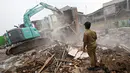 Petugas menyaksikan saat alat berat meratakan bangunan di bantaran Sungai Ciliwung, Bukit Duri, Jakarta, Selasa (12/1). Pemprov DKI membongkar sejumlah bangunan terkait proyek normalisasi Sungai Ciliwung. (Liputan6.com/ Immanuel Antonius)