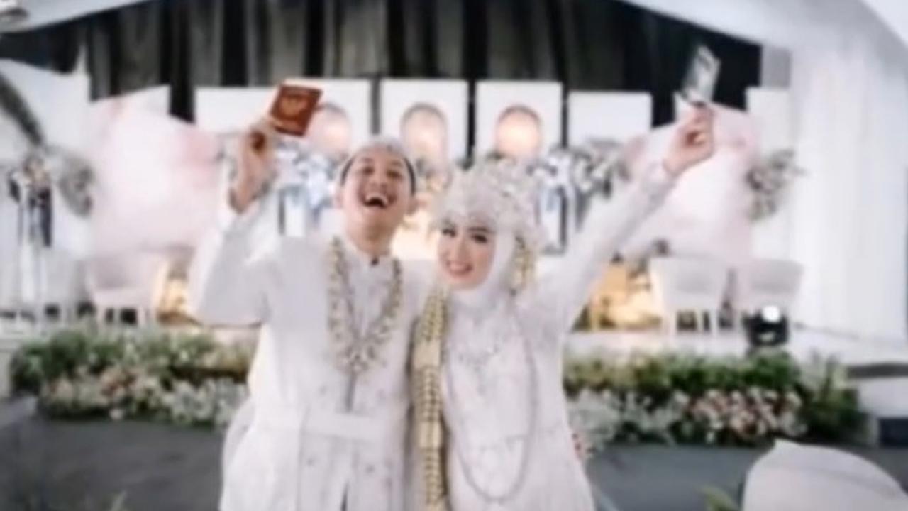 Pose pamer buku nikah jadi pose andalan para pengantin baru. Tapi bagaimana jadinya jika busana adat Sunda tiba-tiba berubah dengan bawahan celana jeans saat diedit.