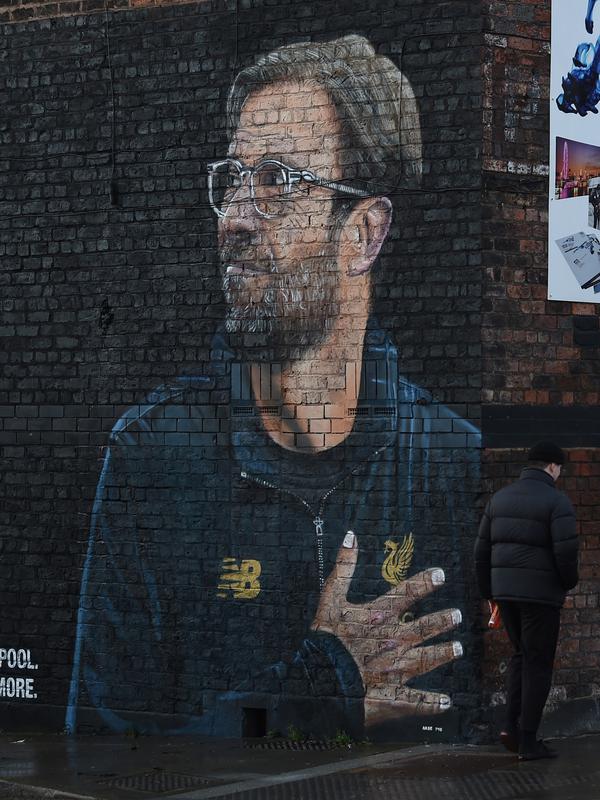 Warga melintas dekat mural pelatih klub Liverpool, Jurgen Klopp di pusat kota Baltic Triangle, Liverpool, Senin (10/12). Banyak yang menyambut pembuatan mural itu namun tidak sedikit pula yang mencibir, termasuk suporter klub Everton. (Paul ELLIS / AFP)
