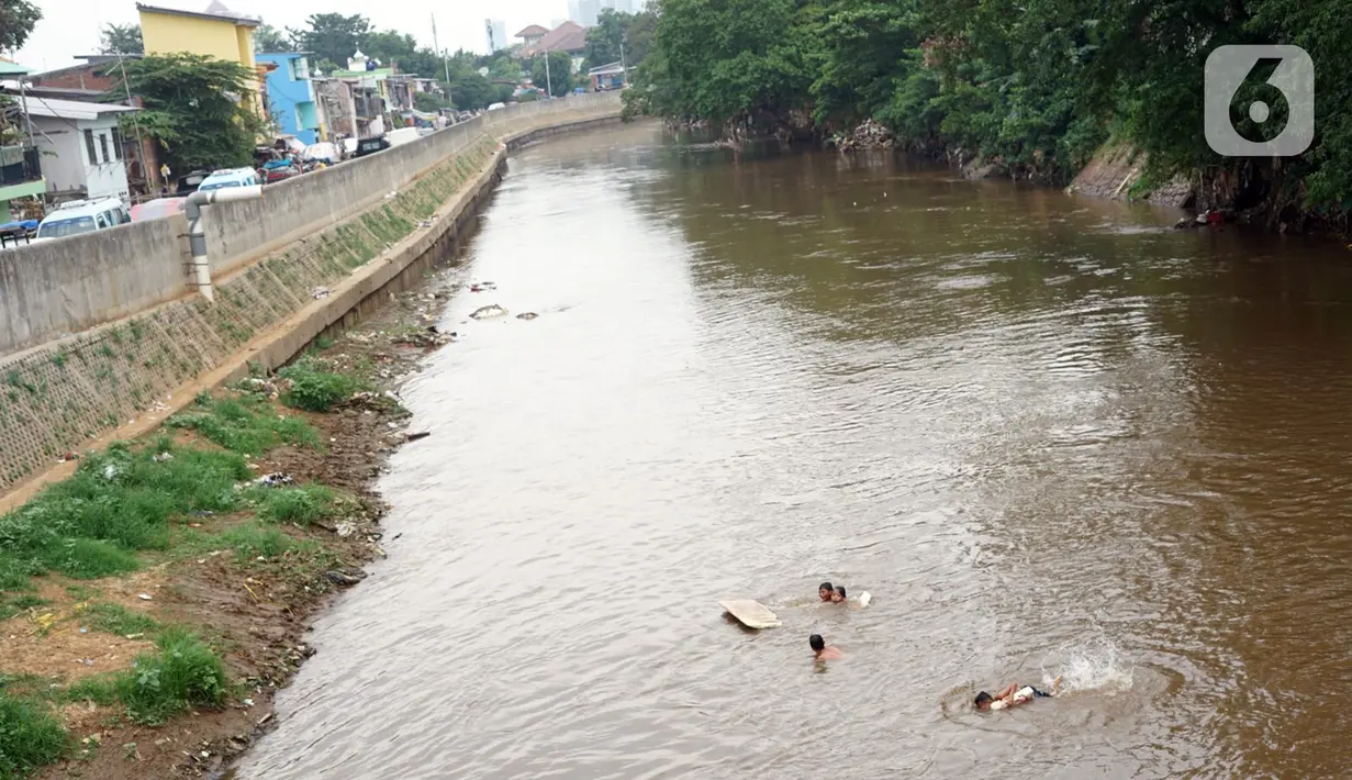 Anak-anak berenang di aliran Sungai Ciliwung, Jatinegara, Jakarta Timur, Sabtu (4/7/2020). Minimnya lahan bermain menyebabkan anak-anak tersebut bermain tidak pada tempatnya, meski dapat membahayakan keselamatan. (Liputan6.com/Immanuel Antonius)