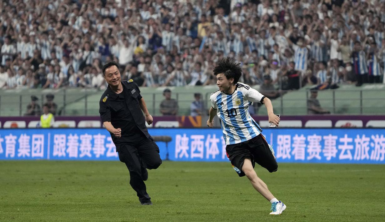Seorang penyusup lapangan berlari menghindari kejaran petugas pada laga persahabatan antara Argentina melawan Australia di Workers' Stadium, Beijing, Kamis (15/06/2023). (AP Photo/Mark Schiefelbein)