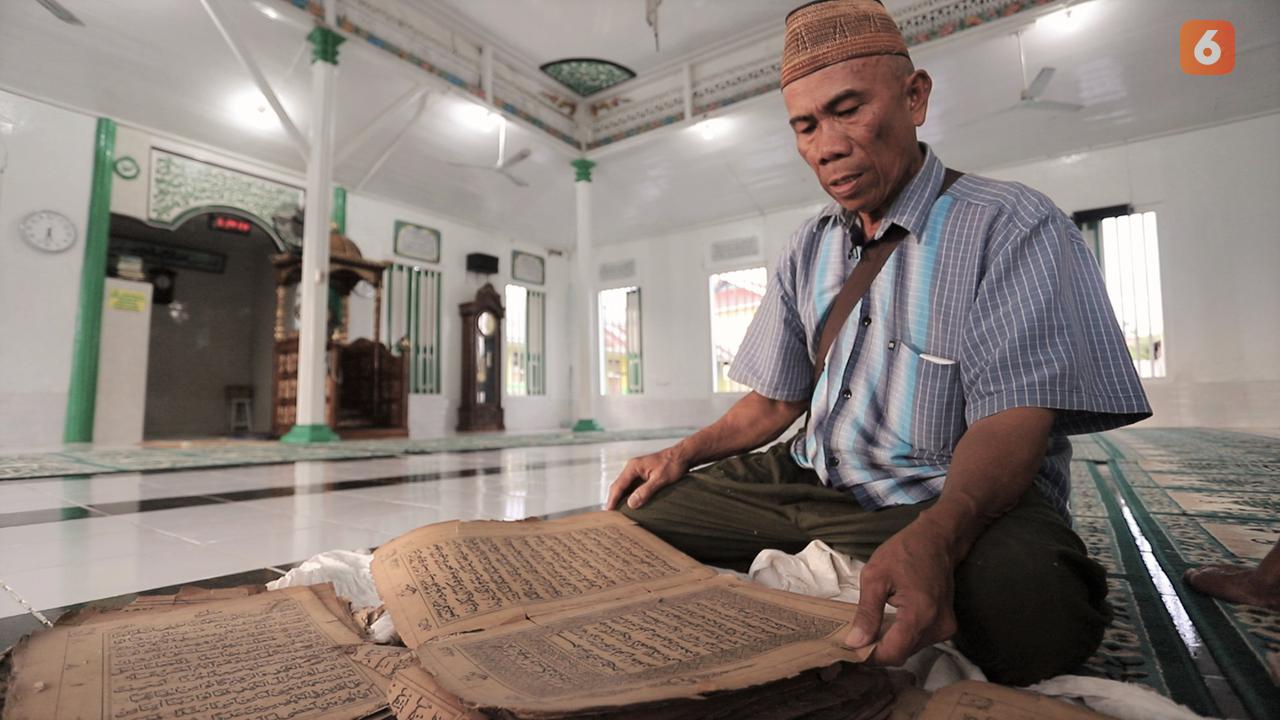 Penjaga Masjid Al Amin memperlihatkan Alquran berusia ratusan tahun