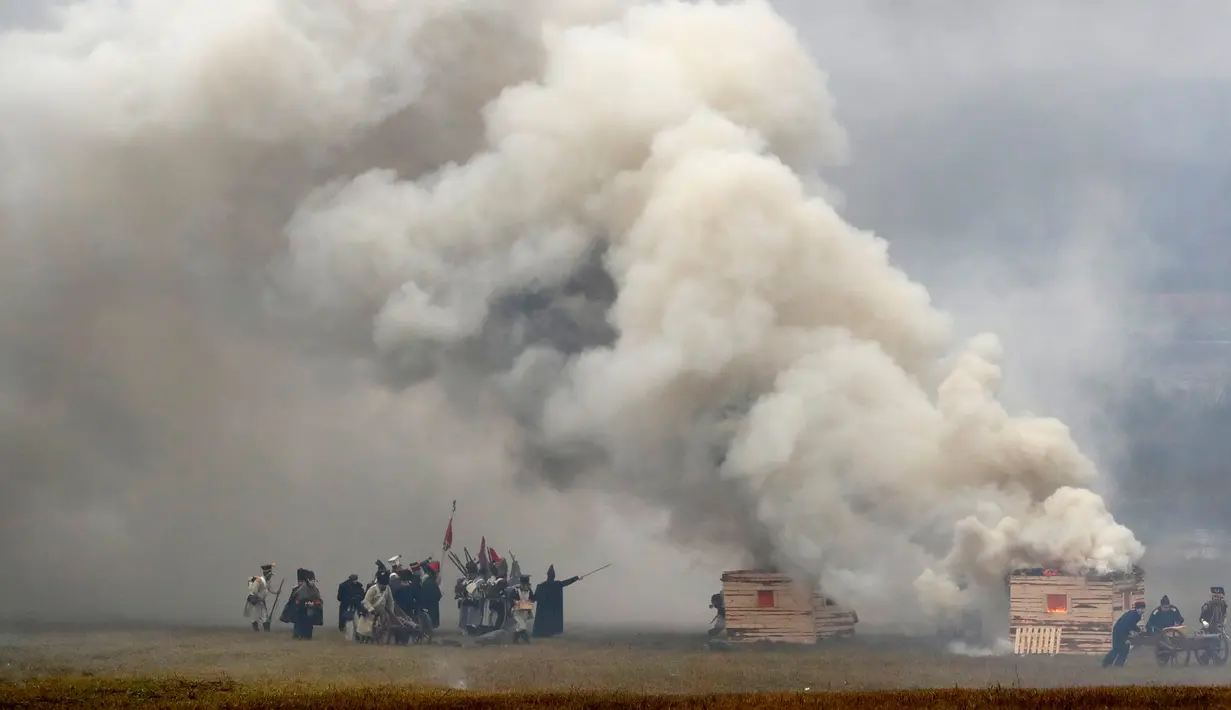 Sejumlah peserta berpakaian seperti tentara Rusia dan Prancis tahun 1812 melakukan adegan pertempuran di Belarus (26/11). Mereka melakukan reka ulang pertempuran Berezina yang terjadi pada tahun 1812.  (AP Photo/Sergei Grits)