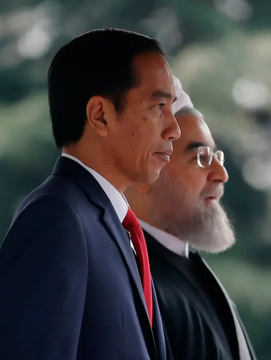 Presiden Joko Widodo bersama Presiden Hassan Rouhani saat mengikuti upacara penghormatan di Istana Saadabad, Rabu (14/12). Dalam kunjungannya, Jokowi akan melakukan pertemuan bilateral, penandatanganan nota-nota kesepahaman. (AFP Photo/Atta Kenare) 
