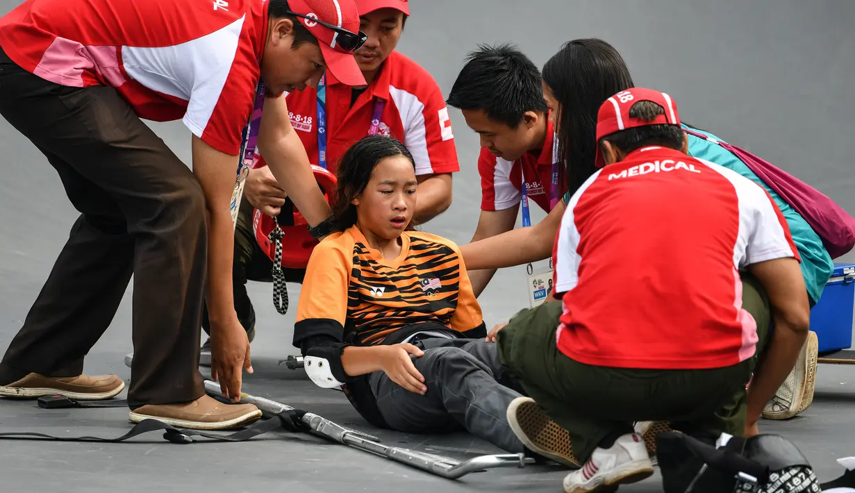 Tim medis menolong skateboarder Malaysia Christina Grace Lai yang cedera saat pemanasan jelang final taman putri Asian Games 2018 di Palembang, Rabu (29/8). Atlet 13 tahun itu terjatuh dengan posisi tertelungkup dan tak bisa bangun lagi. (Mohd RASFAN/AFP)