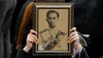 Seorang pelayat wanita memegang foto Raja Bhumibol Adulyadej saat berkumpul di luar Grand Palace sambil menyanyikan rekaman lagu kerajaan untuk menghormati raja mereka, di Bangkok, Thailand, (22/10) (REUTERS/Jorge Silva)