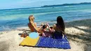 Varsha Strauss Adhikumoro, bersama anak dan temannya berpiknik di pinggir pantai. Mereka menggelar tikar, dan menikmati indahnya laut biru. (Foto: Instagram/@varshaadhikumoro)