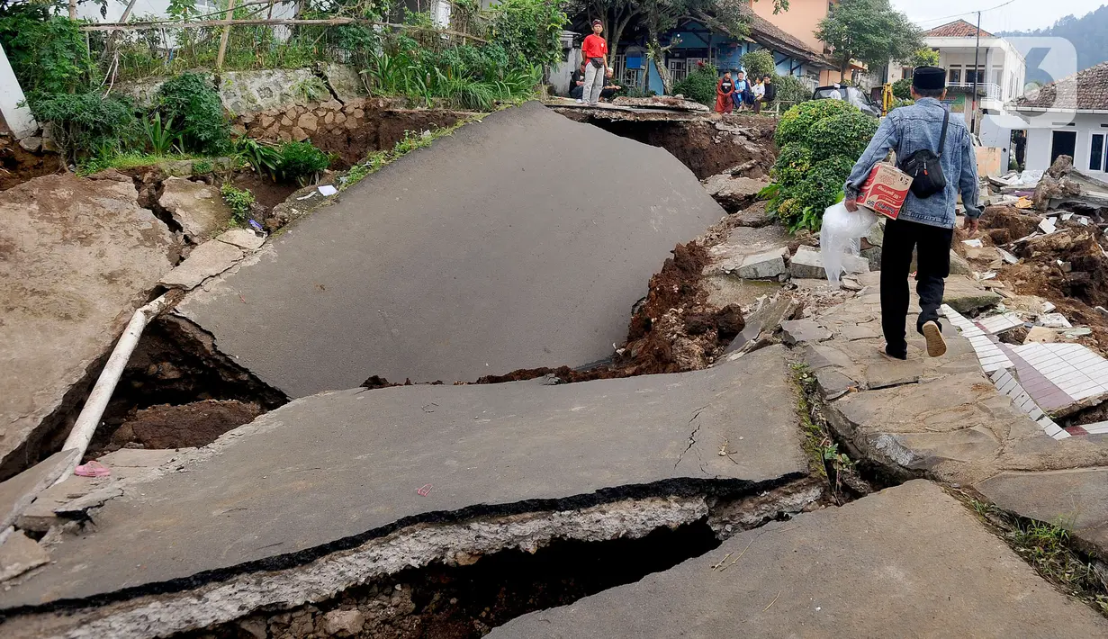Warga melintas di jalan yang rusak parah pascagempa bumi magnitudo 5,6 di Kampung Cisarua, Desa Sarampad, Kabupaten Cianjur, Jawa Barat, Rabu (23/11/2022). Kepala BNPB Letjen TNI Suharyanto mengonfirmasi korban meninggal akibat gempa Kabupaten Cianjur, Jawa Barat, berjumlah 268 orang. (merdeka.com/Arie Basuki)