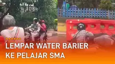 Seorang warga yang terlanjur geram kemudian melempar water barier ke jalan.