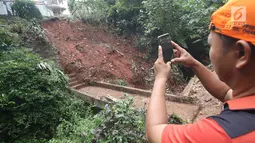Warga mengambil foto longsor yang terjadi di kawasan Ciganjur, Jakarta Selatan, Senin (13/11).  Longsor diduga akibat penumpukan material pembangunan serta hujan deras yang mengguyur Jakarta. (Liputan6.com/Immanuel Antonius)
