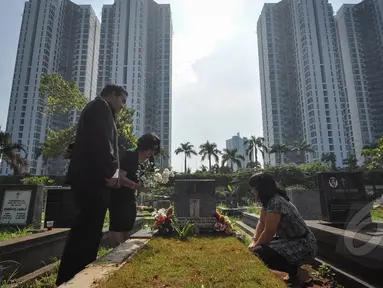 Umat Kristiani tampak berdoa sembari membersihkan makam keluarga dan kerabatnya pada momen Paskah di Menteng Pulo, Jakarta, Minggu (5/4/2015). (Liputan6.com/Faizal Fanani)