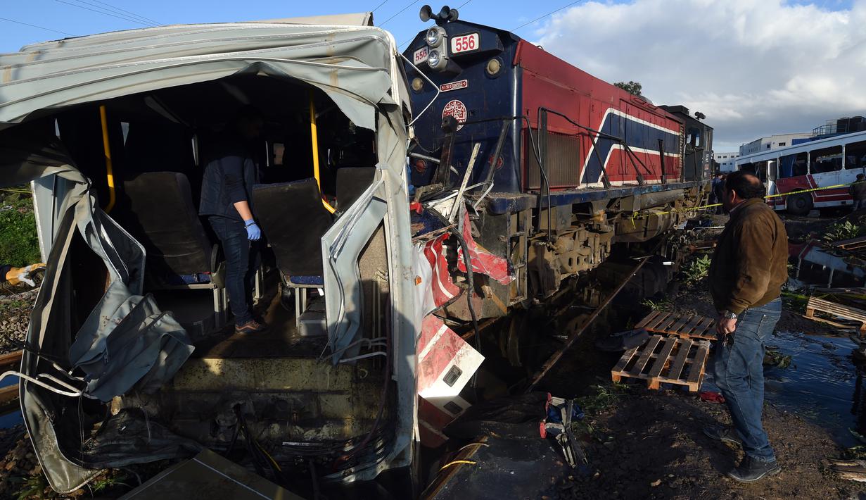 Tim penyelamat memeriksa kondisi bus yang dihantam kereta di rel dekat wilayah Sidi Fathallah, sekitar 10 km selatan Ibu Kota Tunisia, Rabu (28/12). Bus itu terbelah dua ketika dihantam kereta dan menyebabkan lima orang tewas. (Fethi Belaid/AFP)