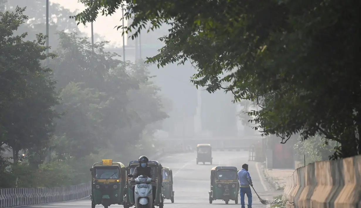 Kendaraan berjalan di sepanjang jalan di tengah kondisi kabut asap tebal di New Delhi (15/11/2021). Otoritas kota New Delhi tengah mempertimbangkan penguncian wilayah akibat kian memburuknya polusi udara. (AFP/Money Sharma)