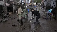 Warga dan tentara bekerja untuk membersihkan lumpur dari jalan-jalan setelah lereng bukit yang diguyur hujan runtuh dan membawa gelombang lumpur ke daerah La Gasca di Quito, Ekuador, Selasa (1/2/2022). (AP Photo/Dolores Ochoa)