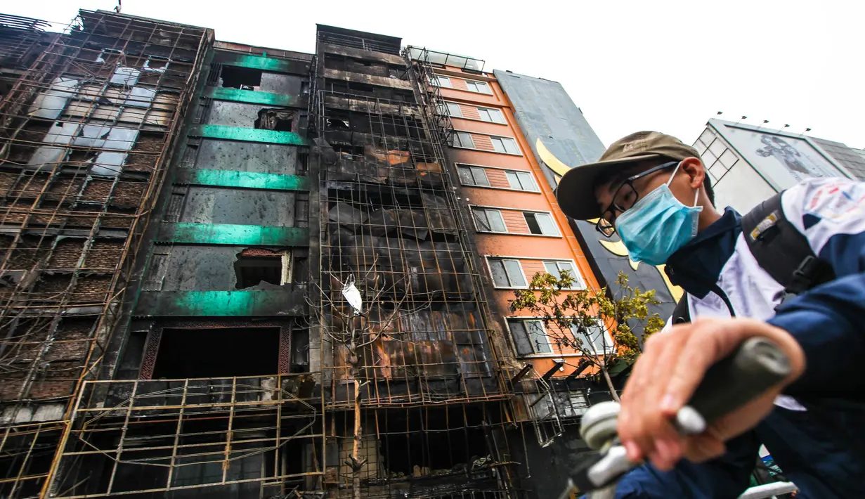 Pengendara sepeda melewati bangunan tempat karaoke yang hangus terbakar di ibu kota Vietnam, Hanoi, Rabu (2/11). Kebakaran tersebut menyebabkan 13 pengunjung yang sedang asyik bernyanyi tewas dan dua polisi terluka. (STR / AFP)