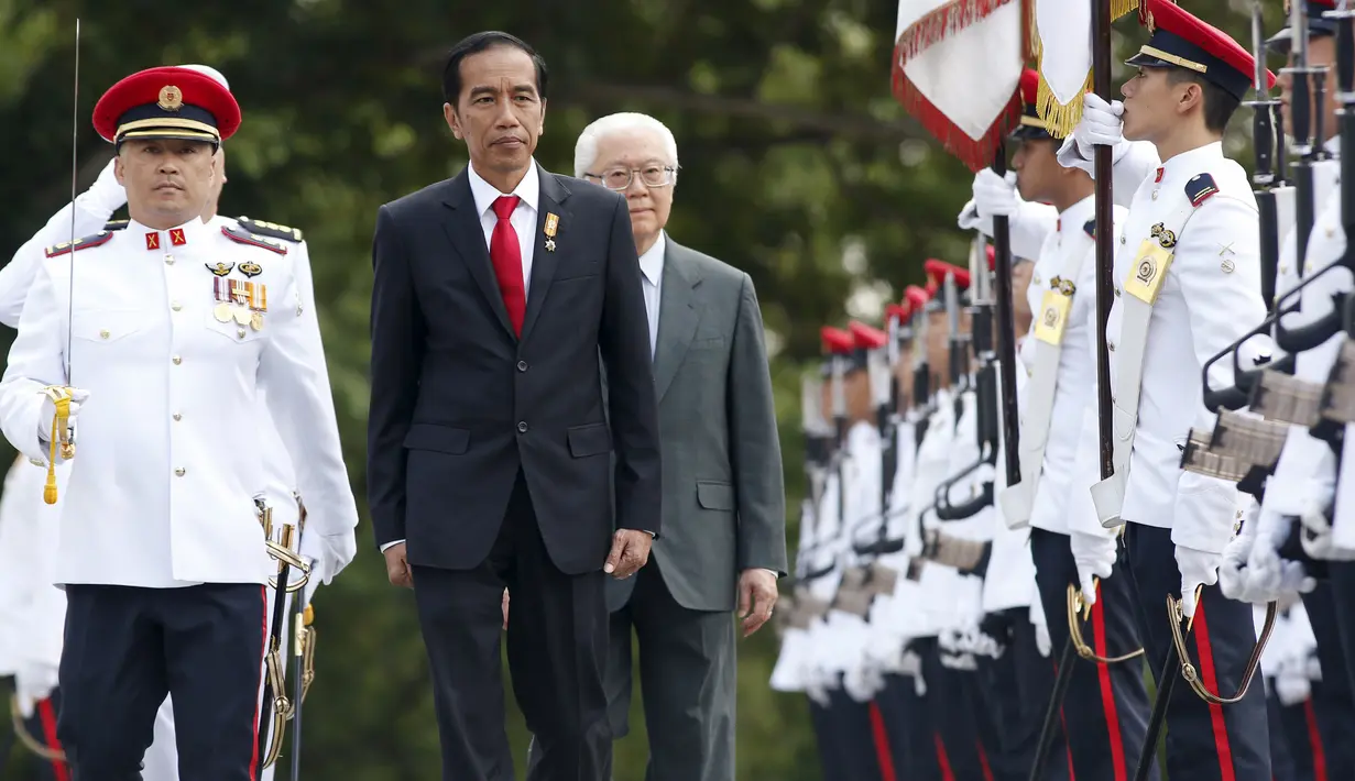 Presiden Jokowi (tengah) berjalan ditemani Presiden Singapura, Tony Tan (kanan) saat menginspeksi barisan tentara dalam seremonial penyambutan di Istana Kepresidenan Singapura, Selasa, (28/7/2015).Jokowi membawa misi ekonomi (REUTERS/Edgar Su)