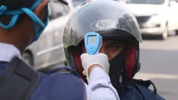 Petugas memeriksa suhu tubuh pengendara saat pelaksanaan Pembatasan Sosial Berskala Besar (PSBB) di kawasan Gading Serpong, Tangerang Selatan, Sabtu (18/4/2020). Pengukuran suhu tubuh tersebut merupakan cek point dari PSBB yang baru saja diberlakukan di Tangerang Raya. (Liputan6.com/Angga Yuniar)